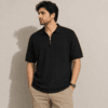 Half zip Black polo model Man wearing a black half zip polo shirt in textured drop needle knit with beige chinos