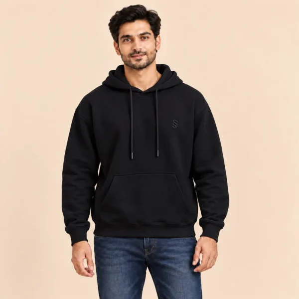 Man wearing the Sportlux Plus black 350 GSM fleece hoodie with tonal embroidered S monogram, relaxed fit, kangaroo pocket, front view