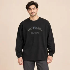 Man wearing the Sportlux Plus black oversized drop shoulder full sleeve t-shirt with tonal STAY POSITIVE KEEP GOING high density screen print, front view