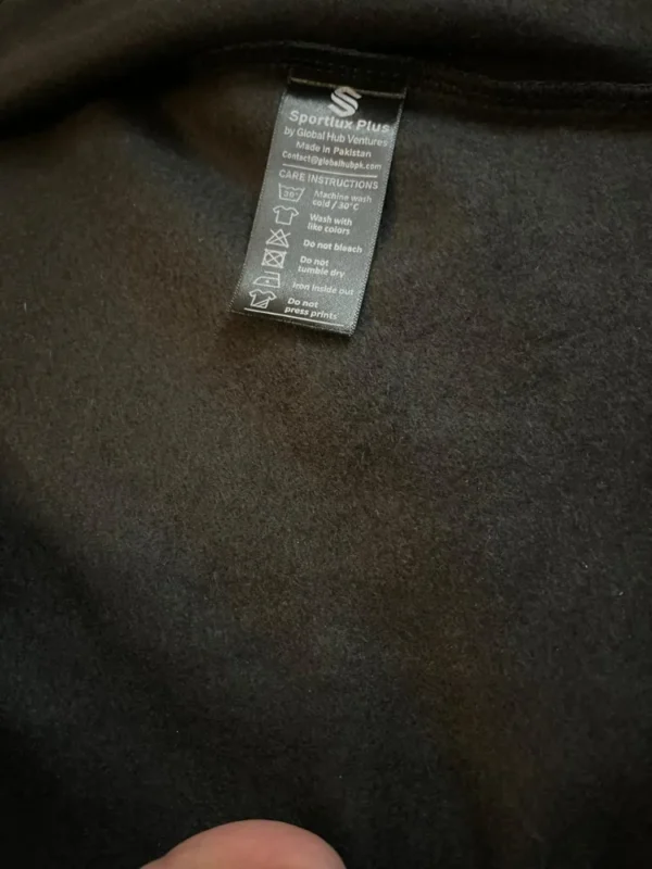 Inside of the Sportlux Plus black hoodie showing the soft brushed fleece and the woven care label, Made in Pakistan