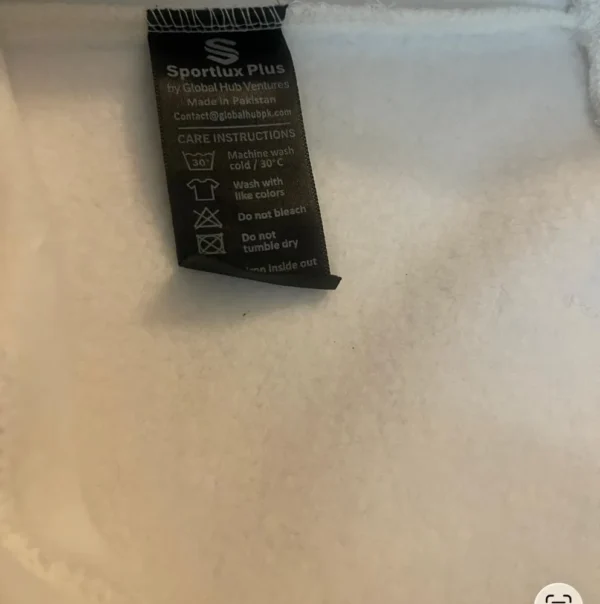 Inside of the Sportlux Plus cream hoodie showing the soft brushed fleece and the woven care label, Made in Pakistan