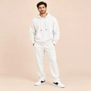 Man wearing the Sportlux Plus cream 350 GSM fleece hoodie co-ord set, relaxed hoodie and straight leg trousers with tonal embroidered S monogram, full length view