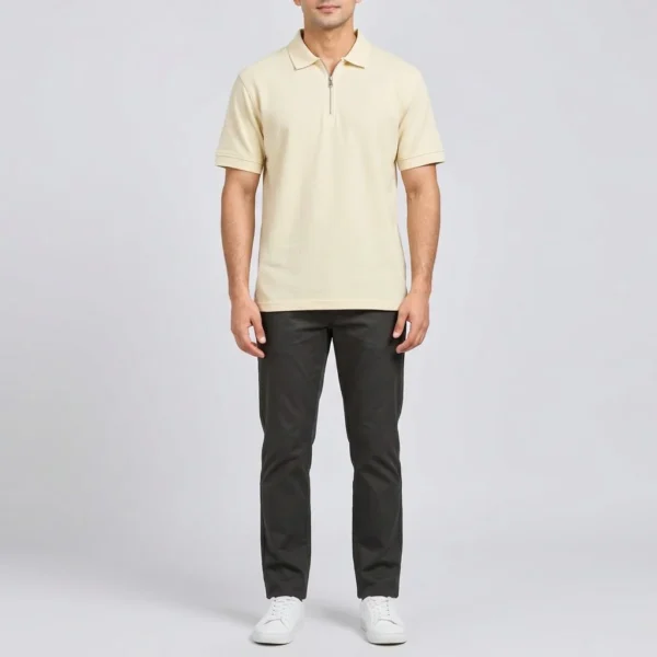 Full length view of the Sportlux Plus cream quarter zip polo worn with charcoal trousers and white trainers, showing the shirt length and fit on an average build